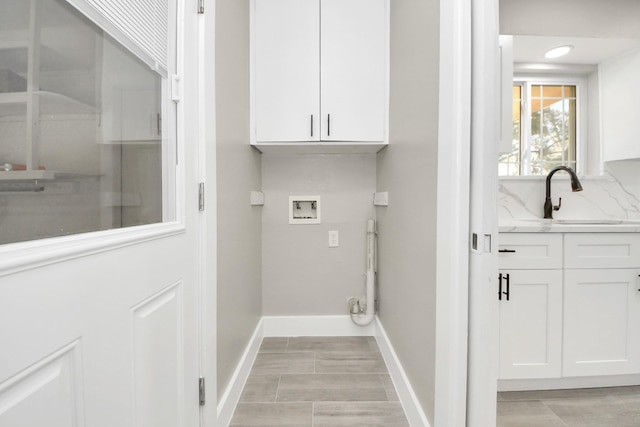 laundry area with cabinet space, baseboards, washer hookup, and a sink