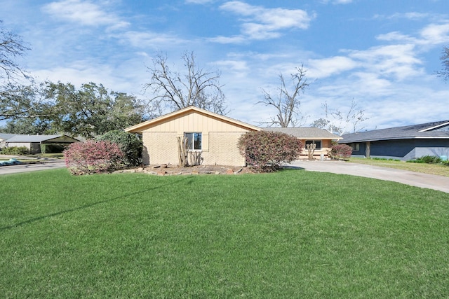 view of front of home with concrete driveway, brick siding, and a front lawn