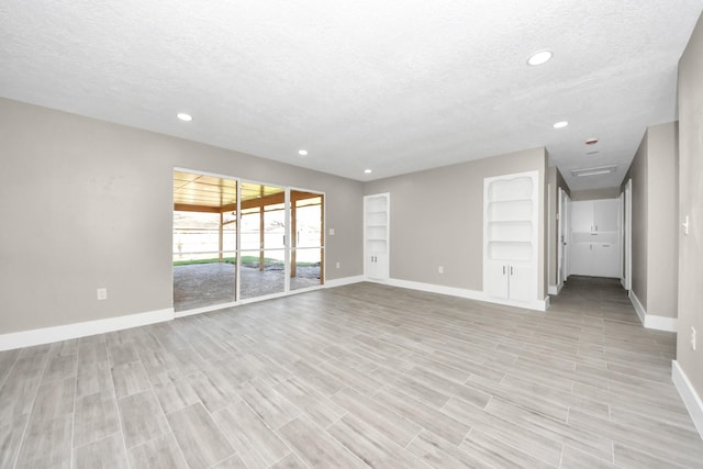 unfurnished living room featuring light wood finished floors, baseboards, a textured ceiling, and recessed lighting