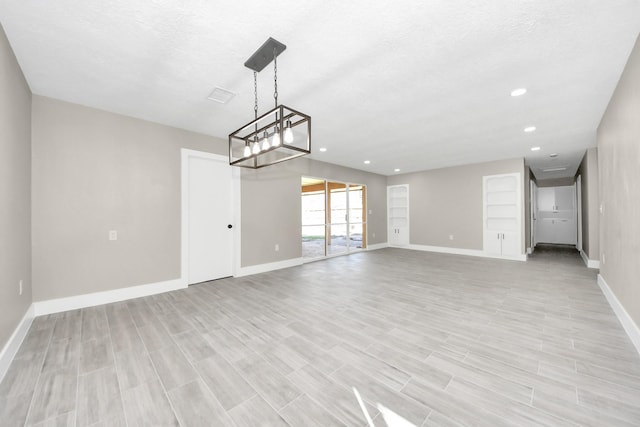 interior space with light wood-style flooring, baseboards, a textured ceiling, and recessed lighting