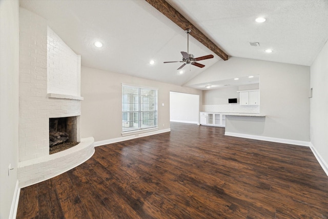 unfurnished living room featuring visible vents, a ceiling fan, lofted ceiling with beams, dark wood-style flooring, and a brick fireplace