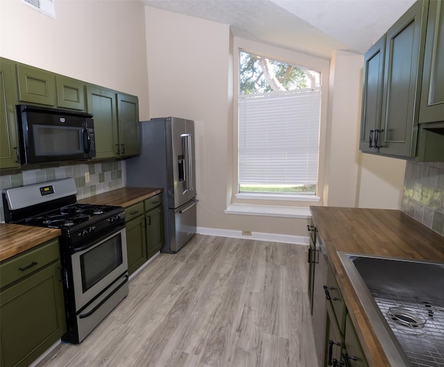 kitchen with green cabinets, wooden counters, decorative backsplash, and stainless steel appliances