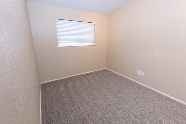 carpeted spare room featuring baseboards