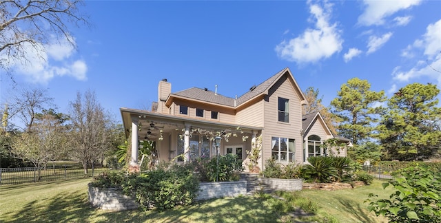 rear view of property featuring covered porch, a chimney, fence, and a yard