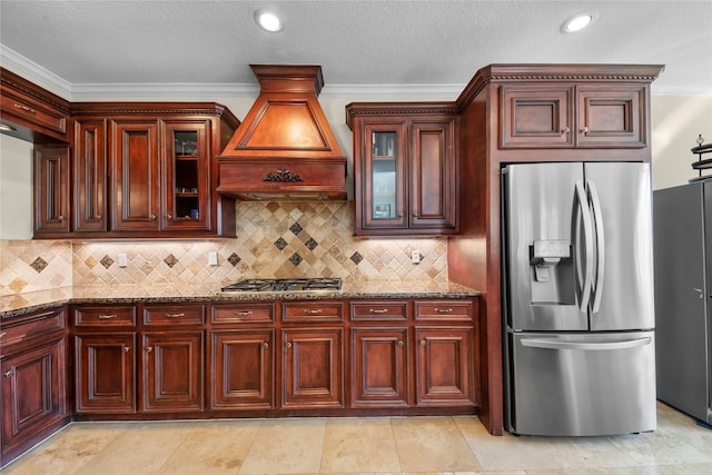 kitchen featuring stainless steel appliances, custom range hood, glass insert cabinets, and light stone countertops