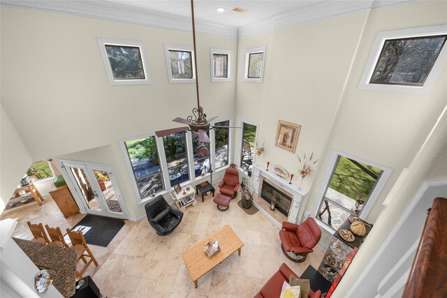 living room featuring a wealth of natural light, a high ceiling, crown molding, and a glass covered fireplace