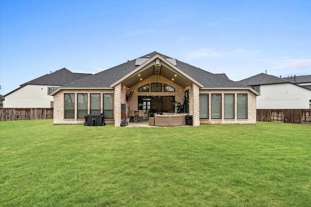 rear view of house with a fenced backyard, a yard, brick siding, and an outdoor hangout area