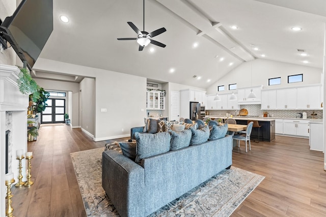 living area with light wood finished floors, a premium fireplace, high vaulted ceiling, and beam ceiling