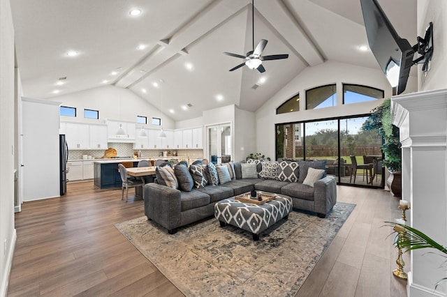 living room featuring high vaulted ceiling, beam ceiling, ceiling fan, and light wood finished floors