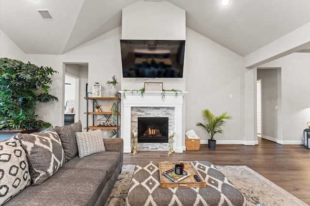 living area featuring vaulted ceiling, wood finished floors, and visible vents