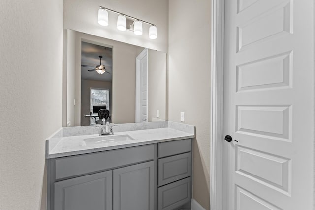 bathroom with a textured wall, a ceiling fan, and vanity