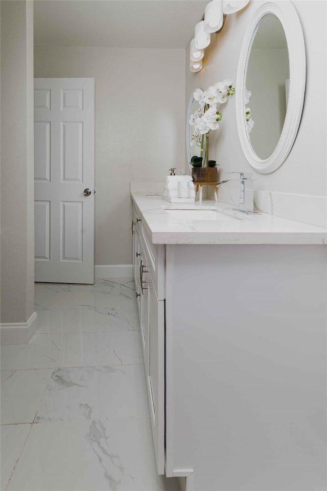 bathroom with marble finish floor, baseboards, and vanity