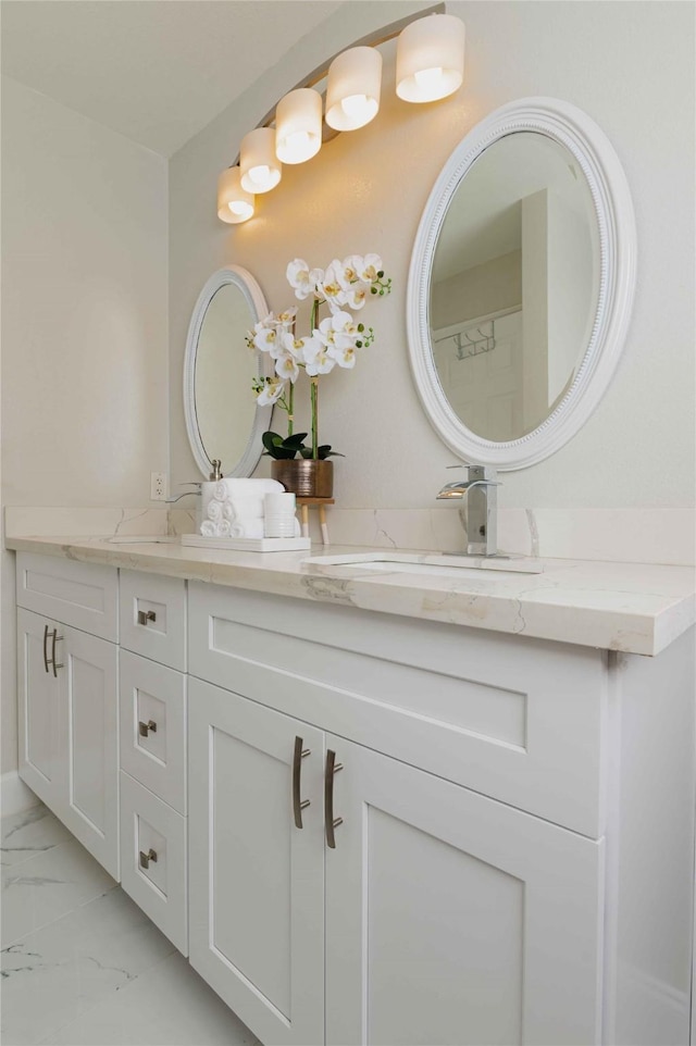 bathroom featuring marble finish floor, double vanity, and a sink