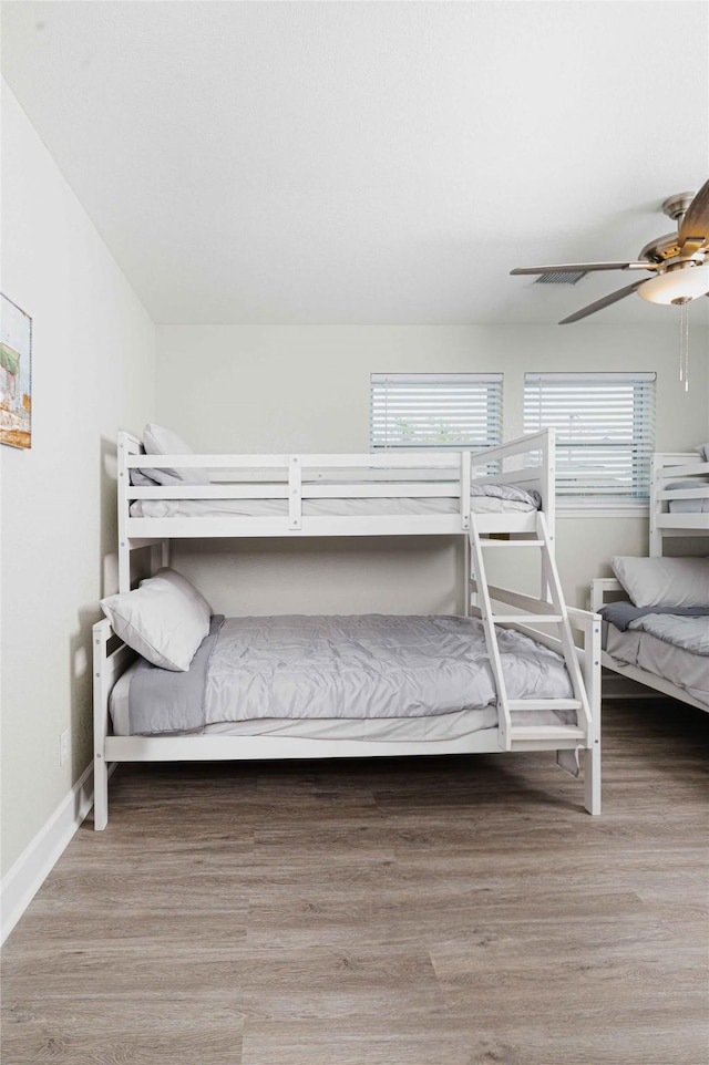 bedroom with wood finished floors, a ceiling fan, and baseboards