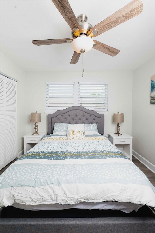 bedroom with a closet, dark wood finished floors, baseboards, and ceiling fan