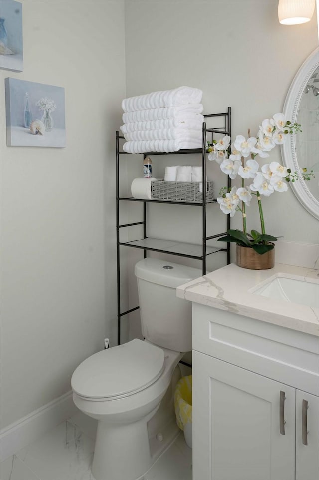 half bathroom featuring toilet, marble finish floor, vanity, and baseboards