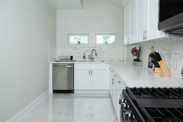 kitchen featuring light stone countertops, white cabinetry, appliances with stainless steel finishes, and a sink