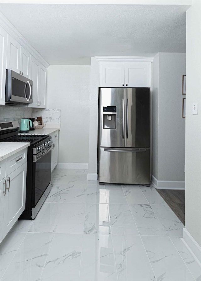 kitchen with marble finish floor, stainless steel appliances, light stone counters, and white cabinets