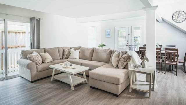 living room featuring plenty of natural light, ornate columns, and wood finished floors