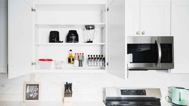 details featuring stainless steel appliances, white cabinetry, backsplash, and open shelves