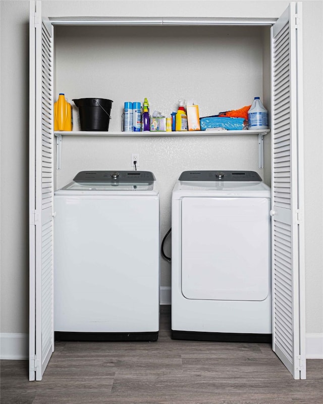 washroom featuring dark wood-type flooring, washing machine and dryer, laundry area, and baseboards