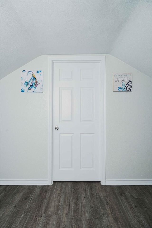 bonus room featuring vaulted ceiling, dark wood finished floors, a textured ceiling, and baseboards