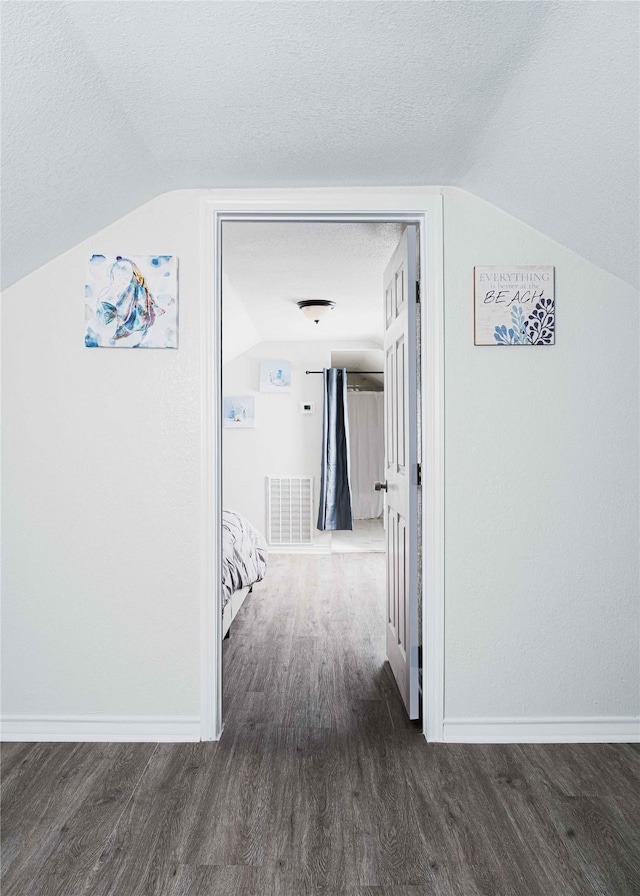 hall featuring baseboards, visible vents, dark wood finished floors, and a textured ceiling