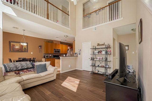 living room featuring a high ceiling, visible vents, and dark wood finished floors