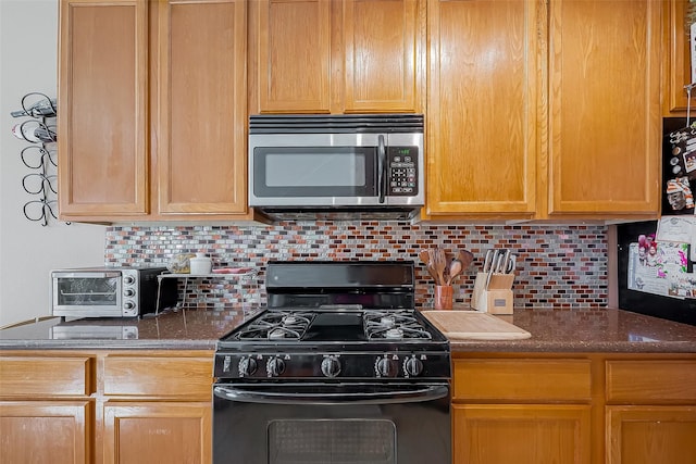 kitchen featuring a toaster, tasteful backsplash, stainless steel microwave, black gas stove, and dark stone counters