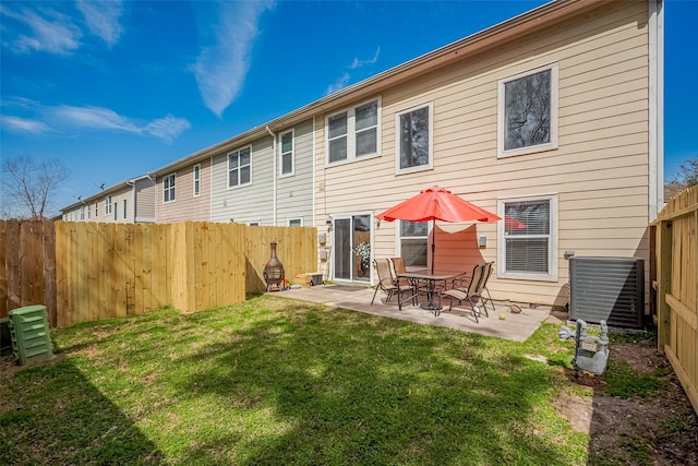 back of house featuring a fenced backyard, a yard, central AC, and a patio