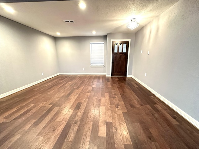 entrance foyer with dark wood-style floors, baseboards, visible vents, and a textured ceiling