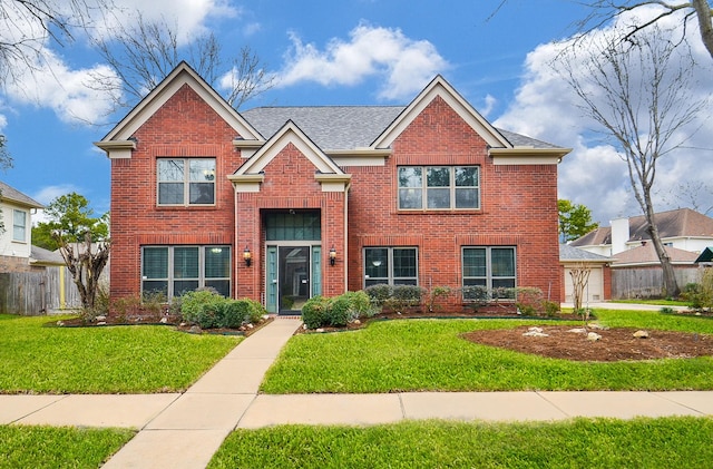 traditional home with a front lawn, an attached garage, fence, and brick siding