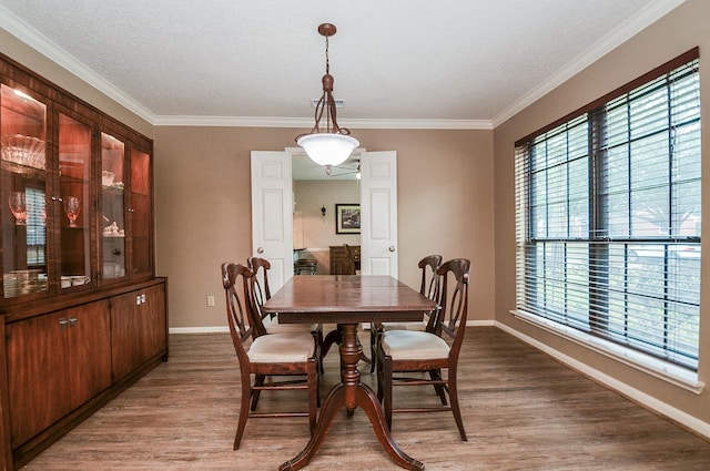 dining area with crown molding, a textured ceiling, baseboards, and wood finished floors