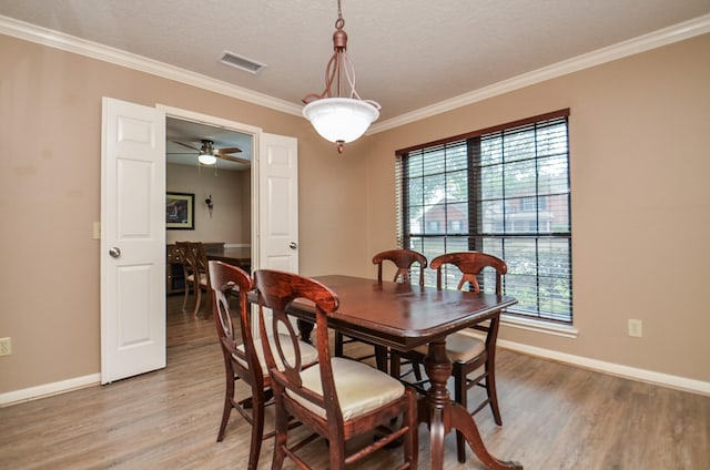 dining room featuring a textured ceiling, baseboards, wood finished floors, and ornamental molding