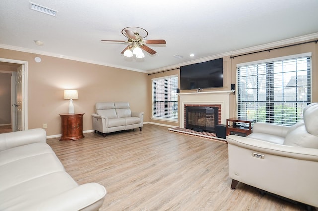 living room with crown molding, a fireplace, visible vents, light wood-style floors, and baseboards