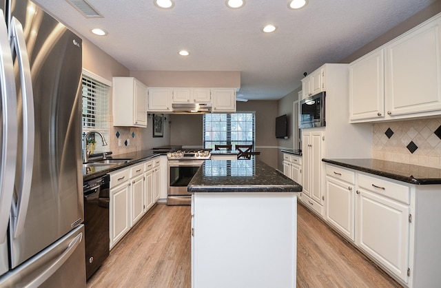 kitchen with a kitchen island, white cabinetry, stainless steel appliances, and a sink