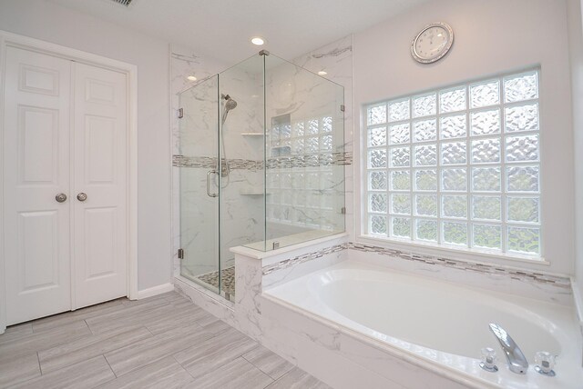 full bathroom featuring a marble finish shower and a bath