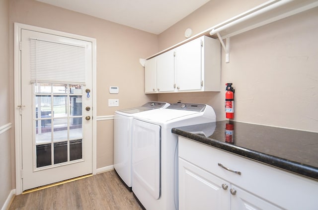 washroom featuring baseboards, light wood finished floors, cabinet space, and washer and dryer