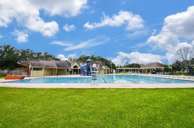 view of swimming pool with playground community and a lawn