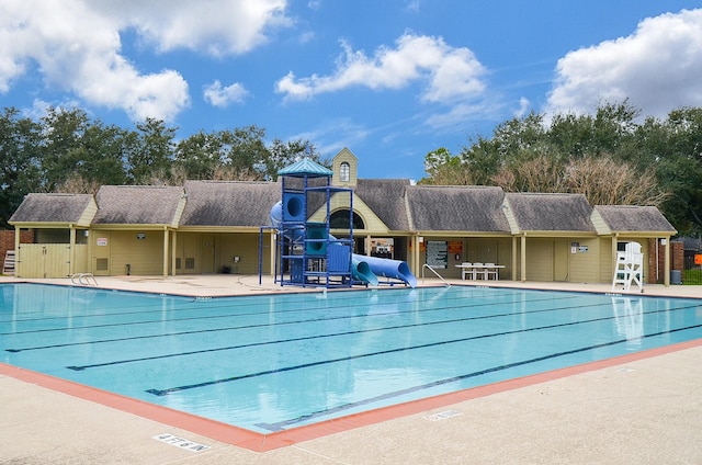 view of swimming pool featuring playground community and a water slide