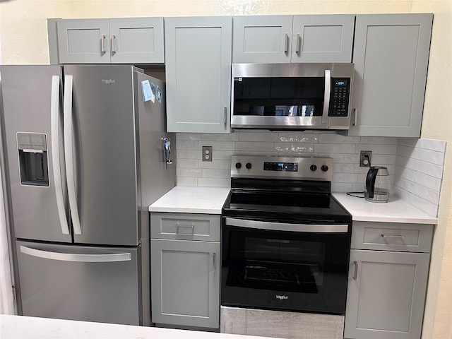 kitchen featuring stainless steel appliances, light countertops, and gray cabinetry