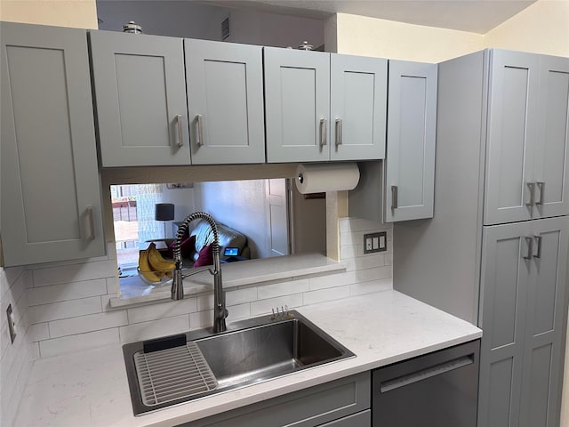 kitchen with black dishwasher, gray cabinets, and a sink