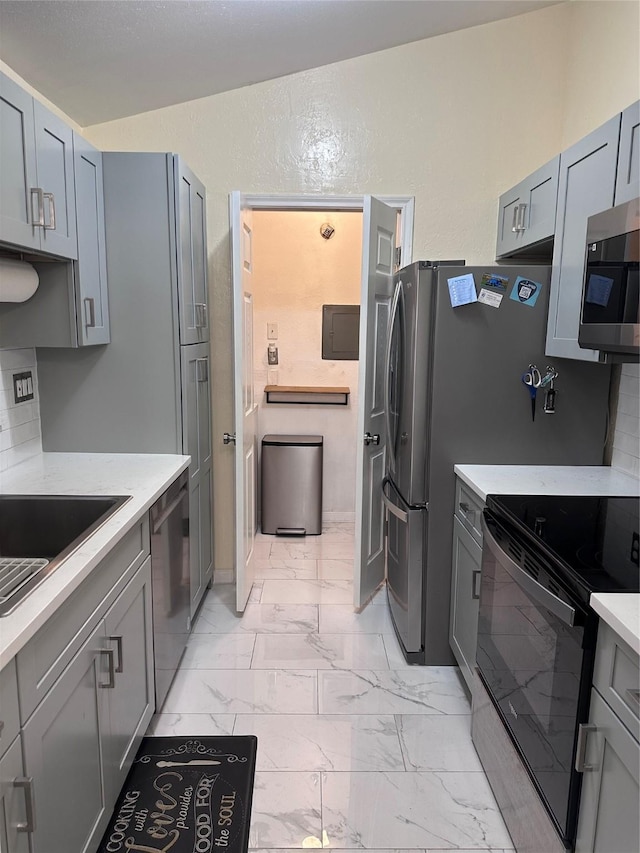 kitchen with marble finish floor, light countertops, appliances with stainless steel finishes, and gray cabinetry