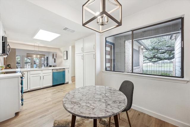 dining space featuring a chandelier, baseboards, visible vents, and light wood finished floors