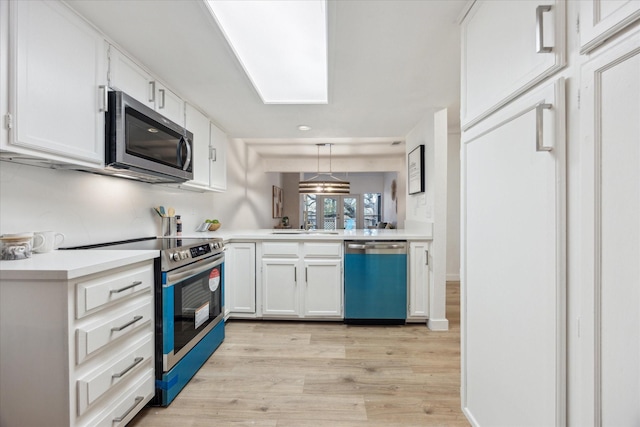 kitchen featuring white cabinets, light wood-style flooring, appliances with stainless steel finishes, hanging light fixtures, and light countertops