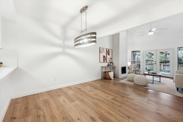 unfurnished room with baseboards, ceiling fan, light wood-style flooring, vaulted ceiling, and french doors