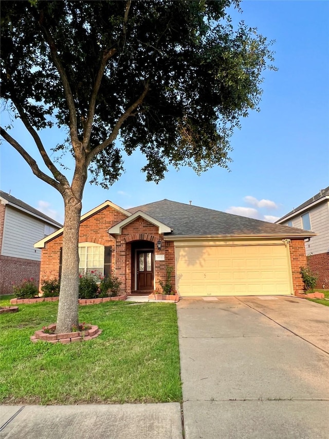 ranch-style home featuring an attached garage, a shingled roof, brick siding, concrete driveway, and a front yard