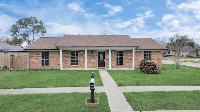 ranch-style home featuring a shingled roof, fence, a front lawn, and brick siding