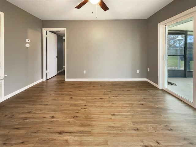 empty room featuring wood finished floors, a ceiling fan, and baseboards