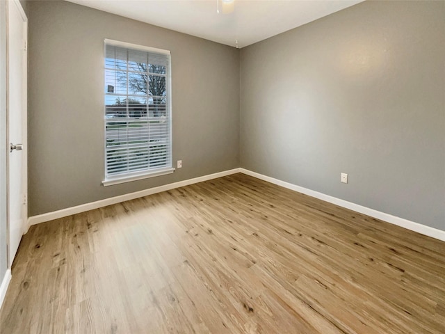 spare room with baseboards, ceiling fan, and light wood-style floors